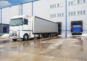 Unloading big container trucks at warehouse building