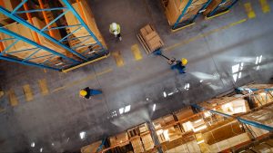 Top-Down View of a Warehouse Worker Using a Motorized Trailer Dolly.